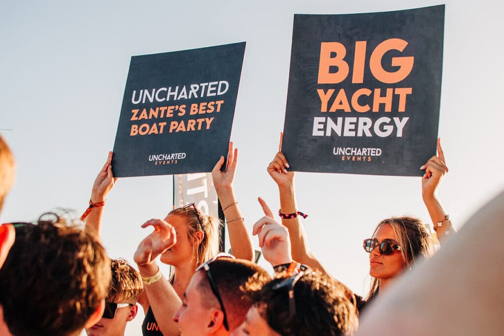 girls holding signs in the vip area on the uncharted boat party in Zante